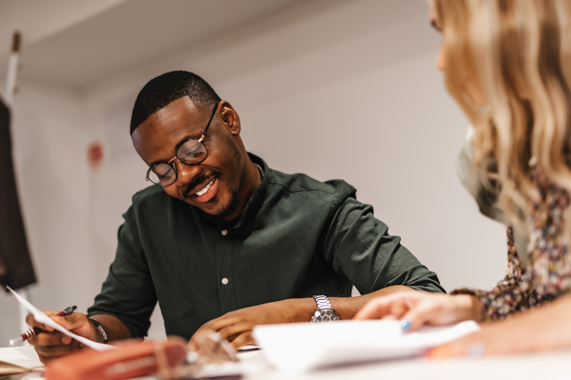 Two smiling people in an office reviewing papers together